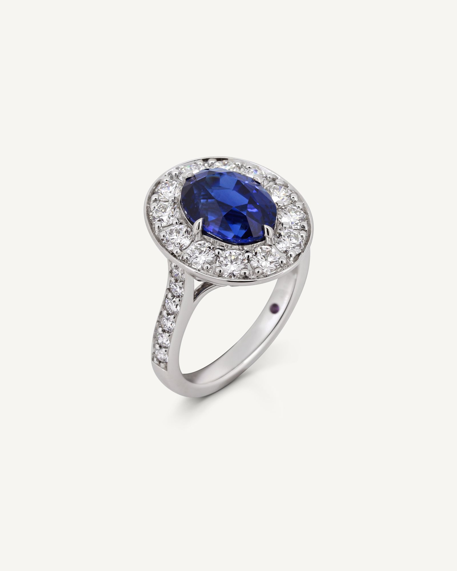 Oval sapphire ring with a round brilliant diamond halo, three-quarter view